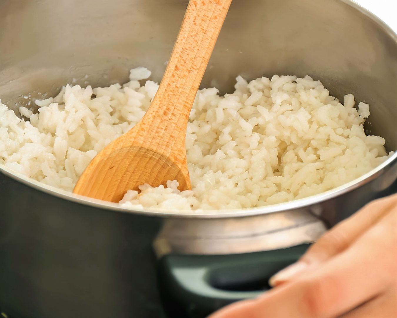 Olla con arroz cocido y una paleta de madera