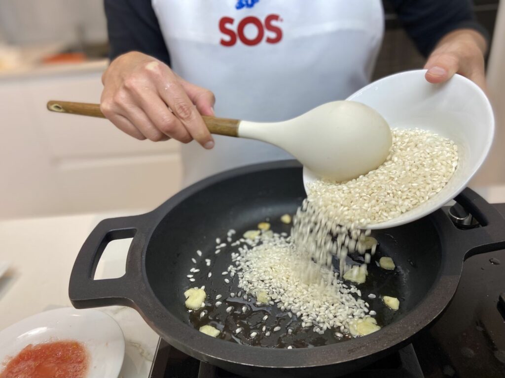 Añadimos a la cazuela el diente de ajo picado y el arroz, y los rehogamos juntos hasta que tomen color.