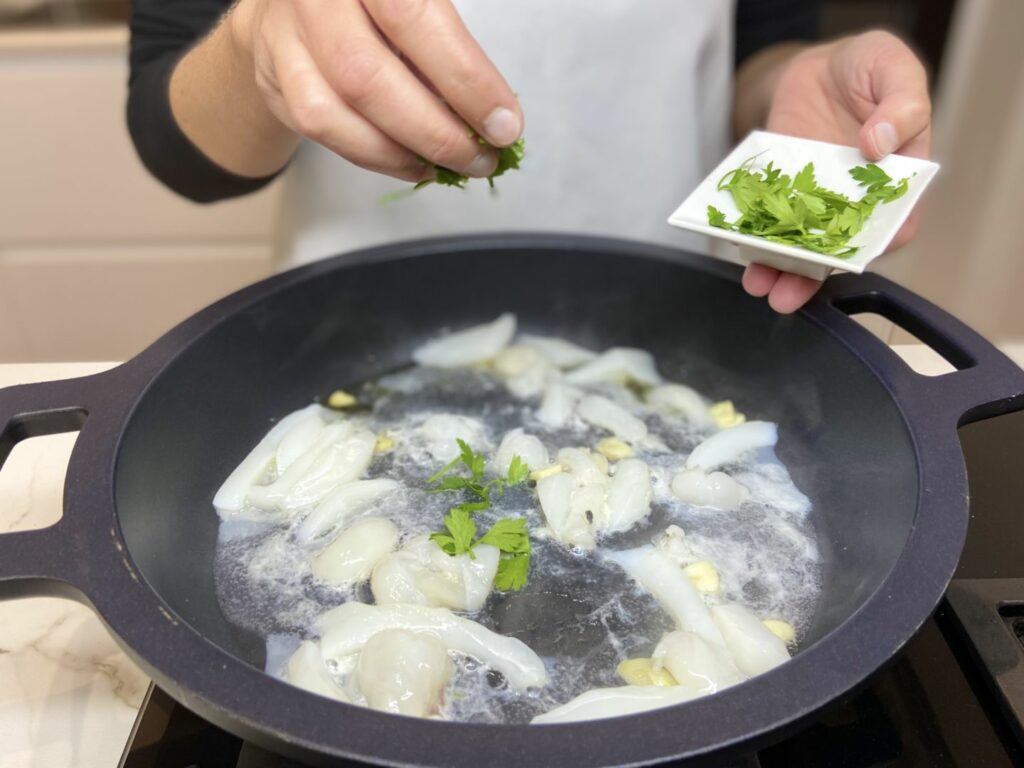Añadimos el calamar, un chorreón de vino blanco y un poco de perejil picado