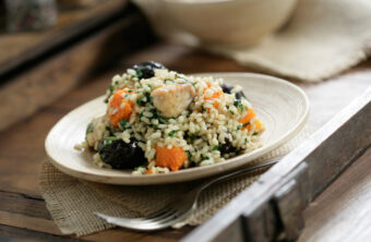 Arroz integral salteado con pollo, calabaza y ciruelas sobre plato blanco