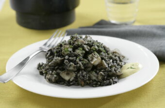 Arroz negro de sepia y chirlas sobre un plato blanco