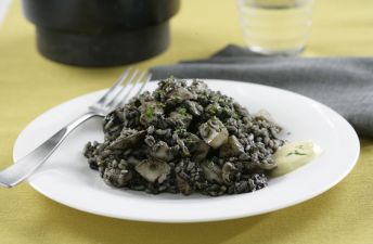 Arroz negro de sepia y chirlas sobre un plato blanco