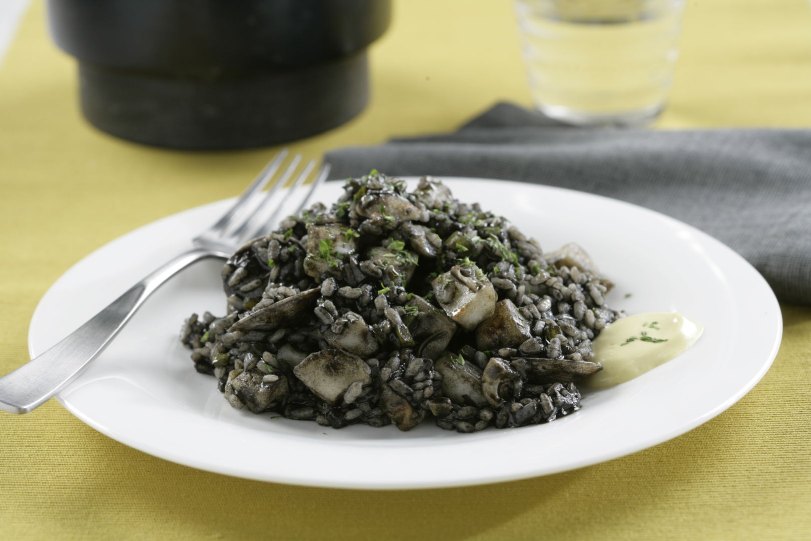 Arroz negro de sepia y chirlas sobre un plato blanco