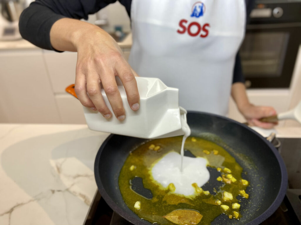 Añadimos la leche de coco y una pizca de sal a la mezcla de la sartén