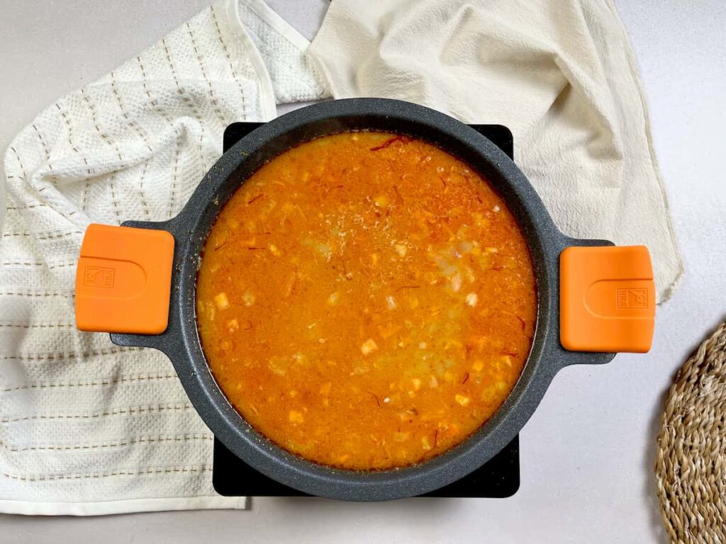 Receta de Arroz con gambones. Añadimos el caldo de pescado y exprimimos la cabeza de los gambones. Dejamos cocer durante 20 minutos
