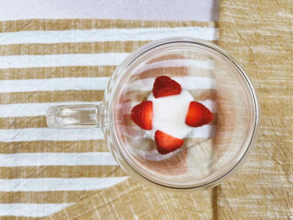 Receta Pudín de chía. Paso 3: Pon en un vaso de postre 2 cucharadas de yogur y algunas fresas. A continuación, añade una primera capa de la mezcla que habíamos reservado en la nevera. Incorpora algunas fresas laminadas. Repite esta operación.