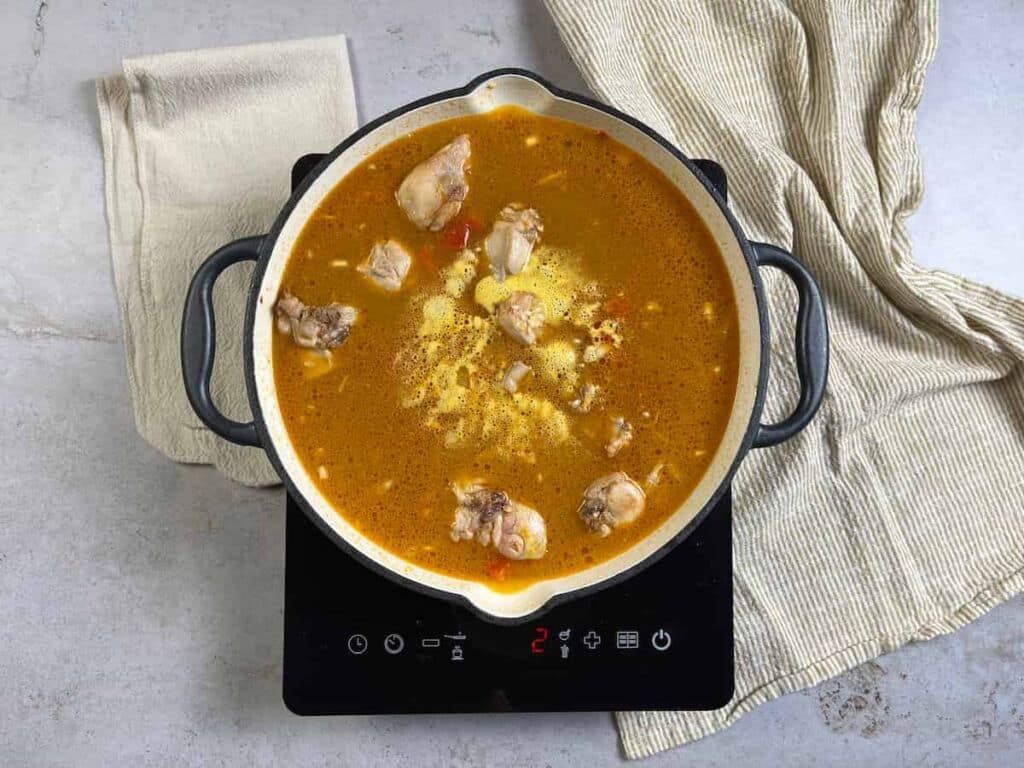 Receta paella de conejo. Paso 3: Vierte el caldo y añade la cúrcuma. Cuece el arroz durante 10 minutos