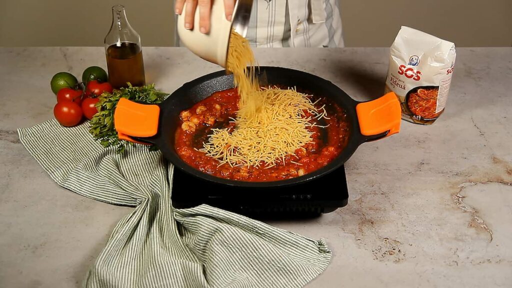 Receta fideuá con gambas. Paso 4: añadir los fideos y el caldo