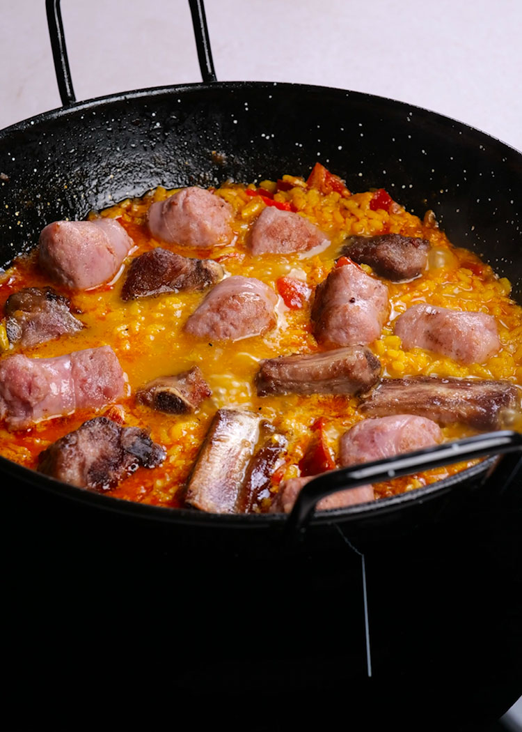 Cocinar arroz e incorporar costillas y butifarras a arroz a la catalana