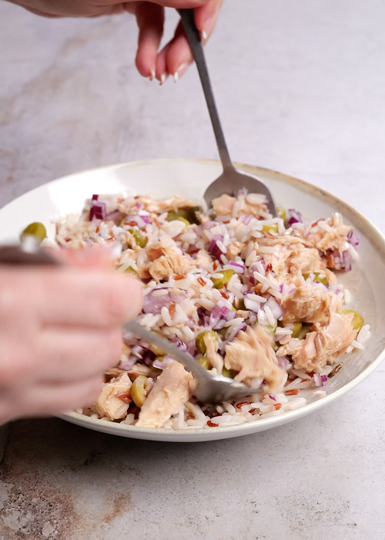 Aliñar y remover ensalada de arroz con tomate y atún
