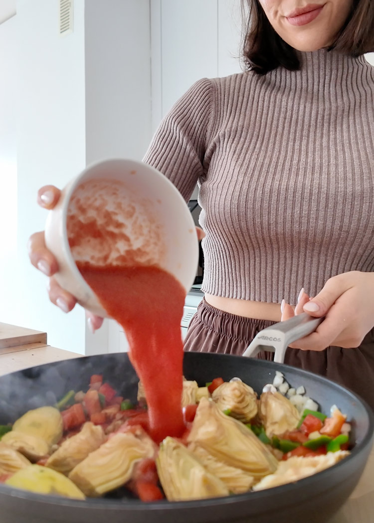 Añadir tomate y pimentón a arroz con alcachofas y verduras
