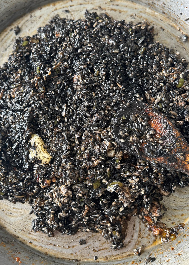 Agregar caldo en paella de arroz negro
